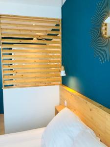 a bedroom with a wooden headboard and a blue wall at Hôtel Café Miramar in Le Grau-du-Roi