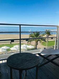 a table and chairs on a balcony with a view of the beach at Hôtel Café Miramar in Le Grau-du-Roi