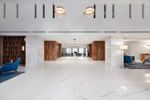 eine Lobby eines Gebäudes mit weißen Böden und blauen Stühlen in der Unterkunft Exe Saldanha in Lissabon