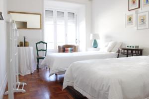 Magnolia Guesthouse في لشبونة: سريرين في غرفة بجدران بيضاء وأرضية خشبية