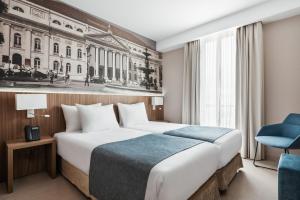 um quarto de hotel com uma cama e uma cadeira azul em Exe Saldanha em Lisboa