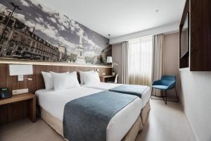 ein Hotelzimmer mit einem großen Bett und einem blauen Stuhl in der Unterkunft Exe Saldanha in Lissabon
