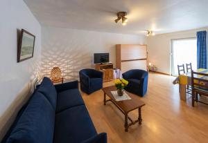 - un salon avec un canapé bleu et des chaises dans l'établissement Meublé Le Coin Tranquille, à Saverne