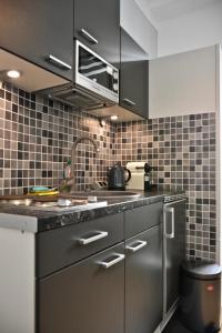 a kitchen with stainless steel appliances and black tiles at Apartments im Thüringer Hof in Berlin