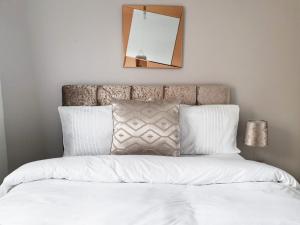 ein Bett mit weißer Bettwäsche und einem Spiegel an der Wand in der Unterkunft Wynn-Griffith Drive - Birmingham BnBs in Tipton