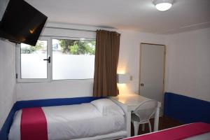 1 dormitorio con cama, escritorio y ventana en Hotel Pachuca Inn, en Pachuca de Soto