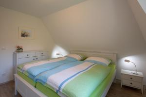 a bedroom with a bed with striped sheets and a dresser at Dat Slott in Pellworm