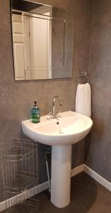 y baño con lavabo blanco y espejo. en Levenhowe Holiday Apartment en Balloch