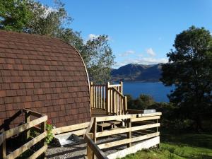 um deque de madeira com uma cerca e vista para a água em The Wee Lodge em Mallaig