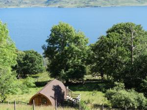 a barn in a field next to a body of water at The Wee Lodge in Mallaig