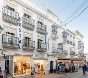 a white building with balconies and a store at Hostal Luna de Nerja HMA 02340 in Nerja