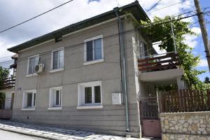 a gray house with a balcony on a street at Стаи за гости "Нина" in Velingrad