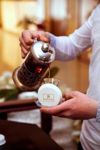 a person is holding a bottle in a coffee pot at Paradise Hotel Baku in Baku