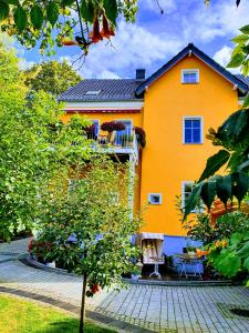 una casa de naranja con balcón y un árbol en APPARTEMENT Friedrich, en Zossen