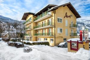 a large building in the snow with a car parked in front at Hotel Alpenhof in Bad Hofgastein