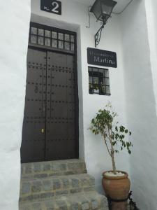 una puerta en una pared blanca con una maceta en El escondite de Martina, Casa Rural Romántica, en Setenil
