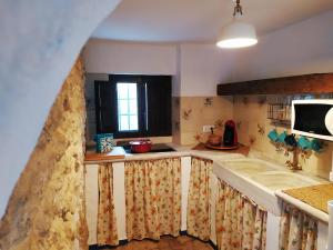 a kitchen with a sink and a microwave at El escondite de Martina, Casa Rural Romántica in Setenil