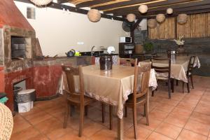 a dining room with tables and chairs and a kitchen at Pousada Casa da Pedra in Blumenau