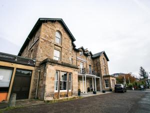 an old brick building with a car parked on the street at The National Hotel in Dingwall