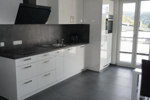 cocina con armarios blancos y encimera negra en Ferienwohnung Schauinsland en Neuenbürg