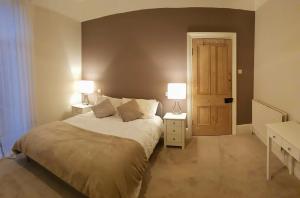 a bedroom with a bed with two lamps and a door at Cottage Grove Homestay rooms in Portsmouth