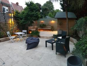 eine Terrasse mit einem Tisch, Stühlen und einer Feuerstelle in der Unterkunft Cottage Grove Homestay rooms in Portsmouth