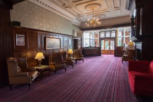 une salle d'attente avec des chaises, des tables et un lustre dans l'établissement Russ Hill Hotel, à Charlwood