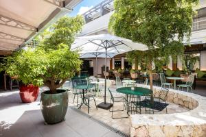 un patio al aire libre con mesas, sillas y árboles en Centr'Hotel en Marigot