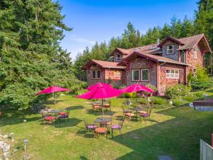 un patio con mesas, sillas y sombrillas rosas en Juniper Lane Guest House en Friday Harbor