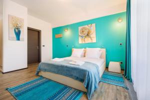 a bedroom with a large bed with a blue wall at Fabulous Panorama Silver Mountain Apartments in Poiana Brasov
