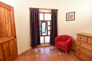 Habitación con silla roja y ventana en Hostal y Cabañas Renta House San Pedro, en San Pedro de Atacama