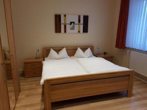 un letto con lenzuola e cuscini bianchi in una camera da letto di Wolthusen a Emden