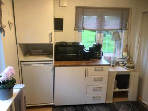 a small kitchen with a microwave and a refrigerator at Villa Lillgården with Sauna and Jacuzzi in Norrköping +10 photos
