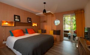 a bedroom with a bed with orange and blue pillows at Le Lodge du Cap Ferret in Cap-Ferret