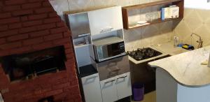 a kitchen with a refrigerator and a brick wall at Recanto dos Albatrozes in Boicucanga