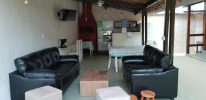 a living room with two leather chairs and a table at Recanto dos Albatrozes in Boicucanga