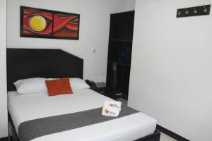 a bedroom with a white bed with a painting on the wall at Hotel Cafeira in Pereira