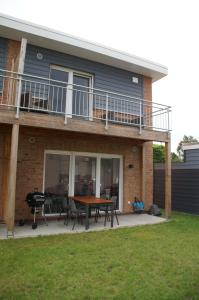 a house with a patio with a table and a balcony at Ferienhaus - Heimathafen Tossens in Butjadingen
