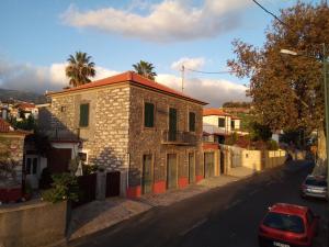 ein kleines Steingebäude auf einer Straße mit Auto in der Unterkunft Victoria 1942 in Funchal