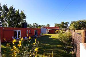 ein Haus mit einem Hof mit gelben Blumen in der Unterkunft LEKU Lodge & Deptos in General Acha