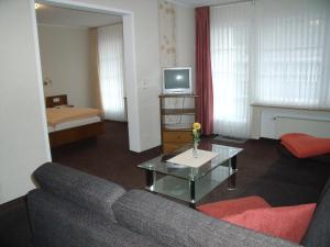 a living room with a couch and a tv at Pension Beste-Schnurbus in Schmallenberg