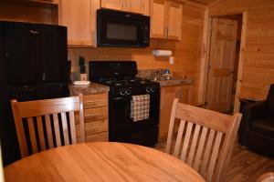 a kitchen with a black stove and a microwave at Tall Chief Camping Resort Cottage 1 in Pleasant Hill