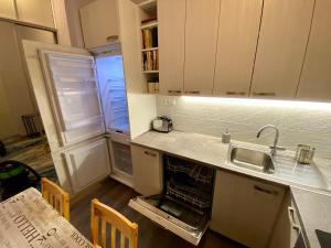 a kitchen with an open refrigerator and a sink at Kings main square Apartment - AC - Balcony - Coffee Machine - Washer - Kitchen- Parking in Poprad
