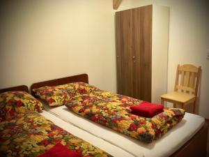 um quarto com 2 camas com capas coloridas e uma cadeira em Statek Kaštan em Rokytnice v Orlickych Horách