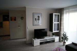 a living room with a television on a white cabinet at Ferienwohnung Im Alftal, Bleialf in Bleialf