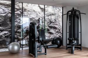 a room with a gym with a stone wall at Miramonti Boutique Hotel in Avelengo