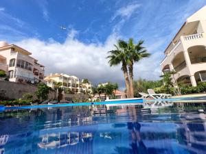 a pool at a resort with palm trees and buildings at Cosy Well Located Apartment Tenerife Sur Golf in San Miguel de Abona