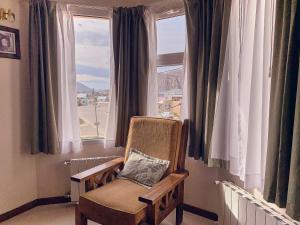 einen Stuhl in einem Zimmer mit Fenster in der Unterkunft Hotel Cumbres Nevadas in El Chalten