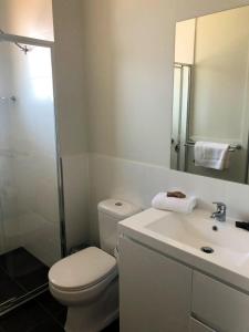 a white bathroom with a toilet and a sink at The Grounds at Callaghan in Jesmond