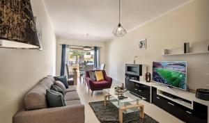 a living room with a couch and a tv at Apartamento Amarelo in Conceição